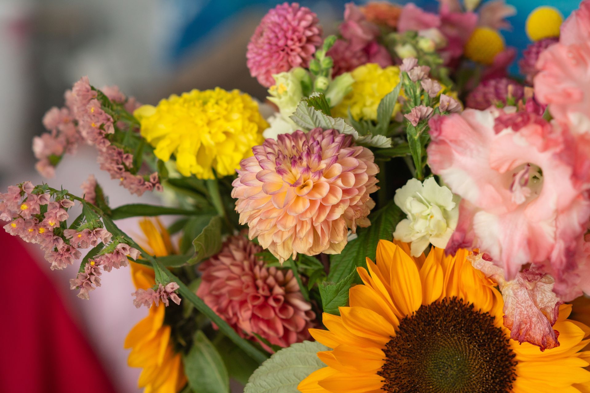 Vibrant bouquet: sunflowers, dahlias, gladiolus, and other colorful flowers arranged together.