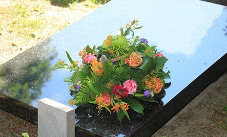 Semplice bouquet di rose e altri fiori su una tomba di marmo nero lisa