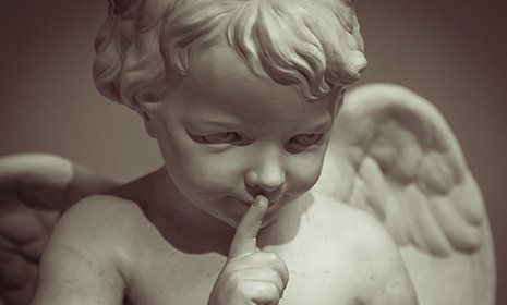 La faccia di un piccolo angel di pietra che chiede silenzio
