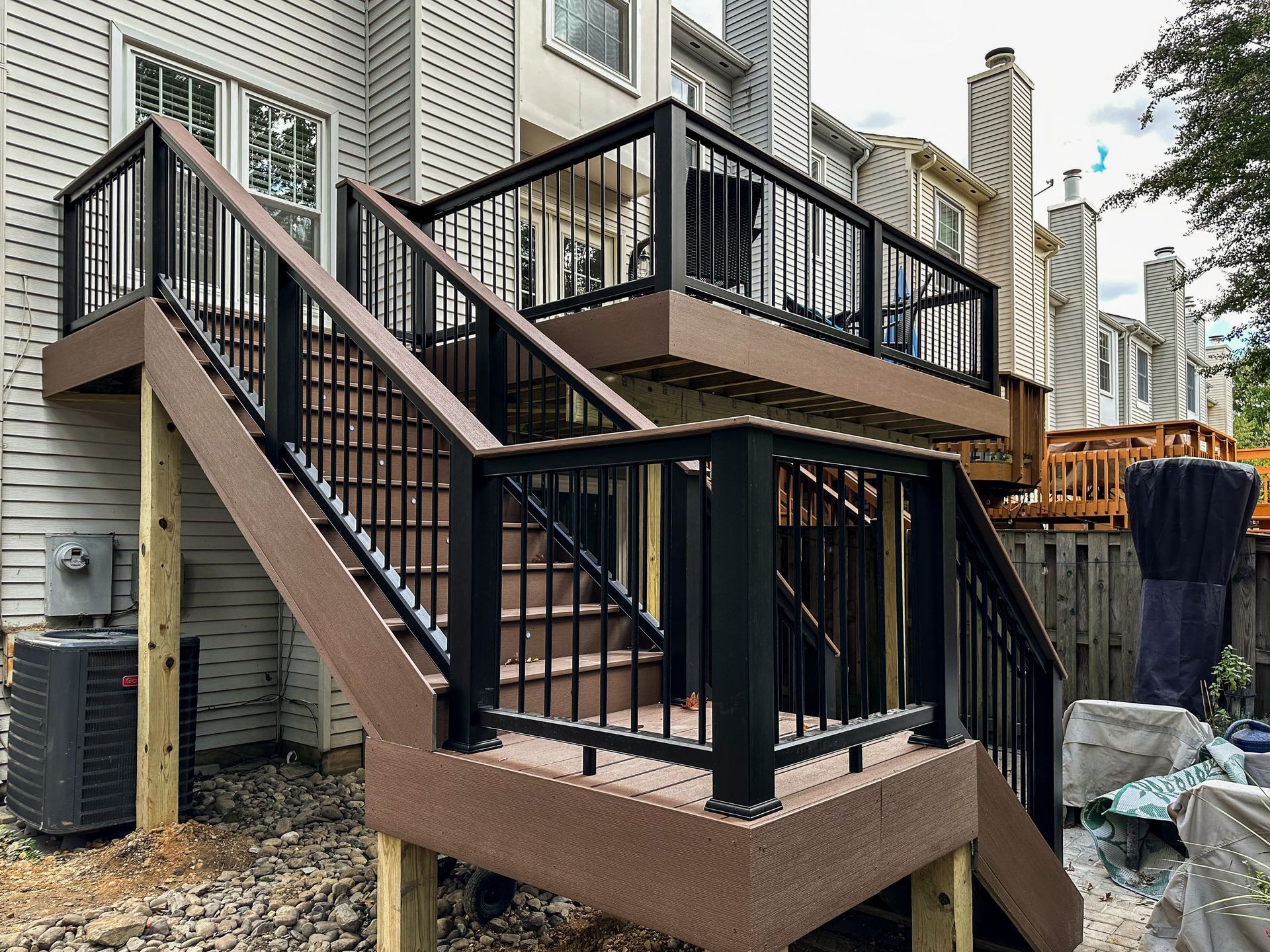 Multi-level deck with black railing and brown composite decking. Outdoor setting.