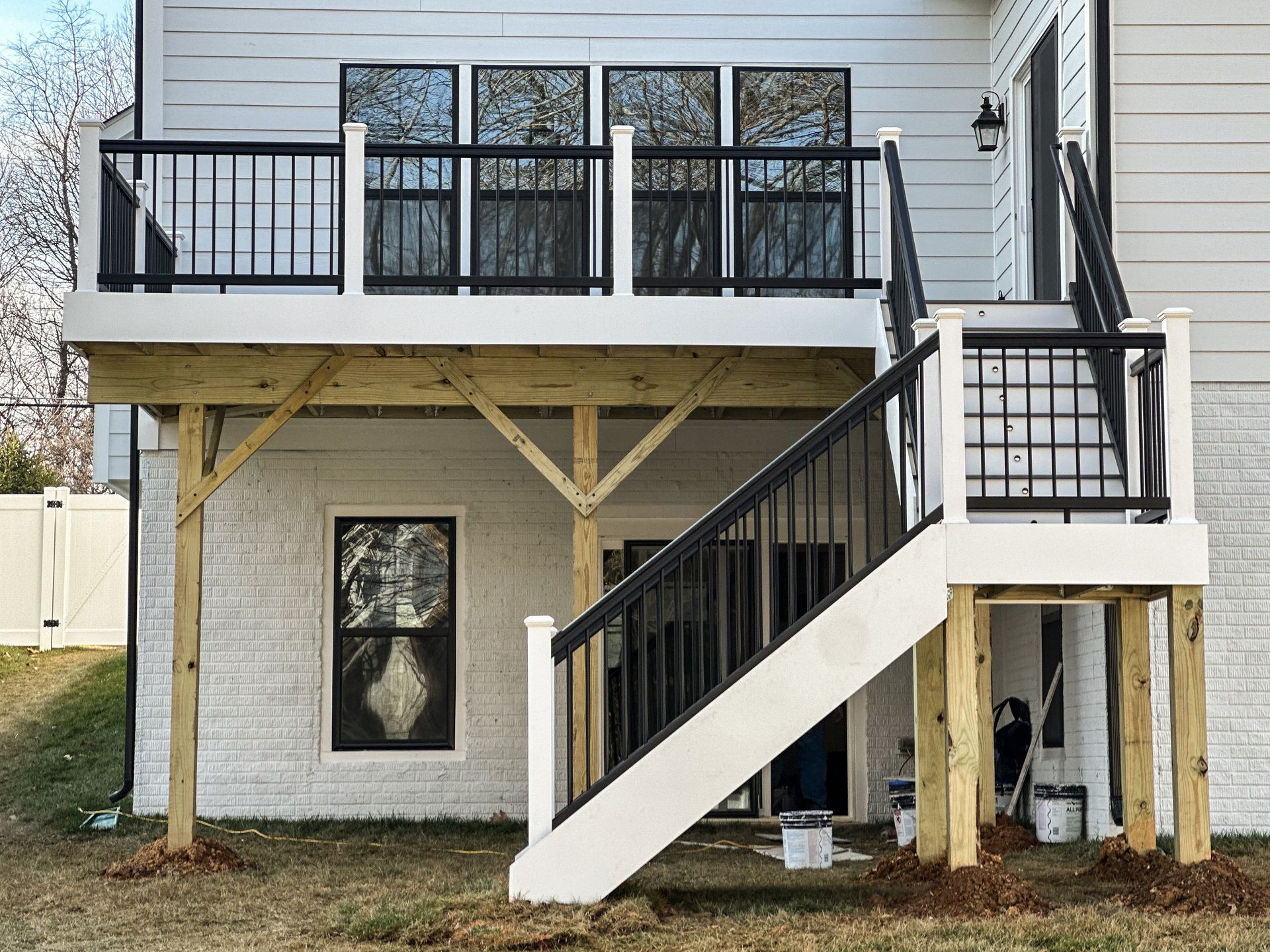 White and black deck with stairs leading down. The deck has black railings.