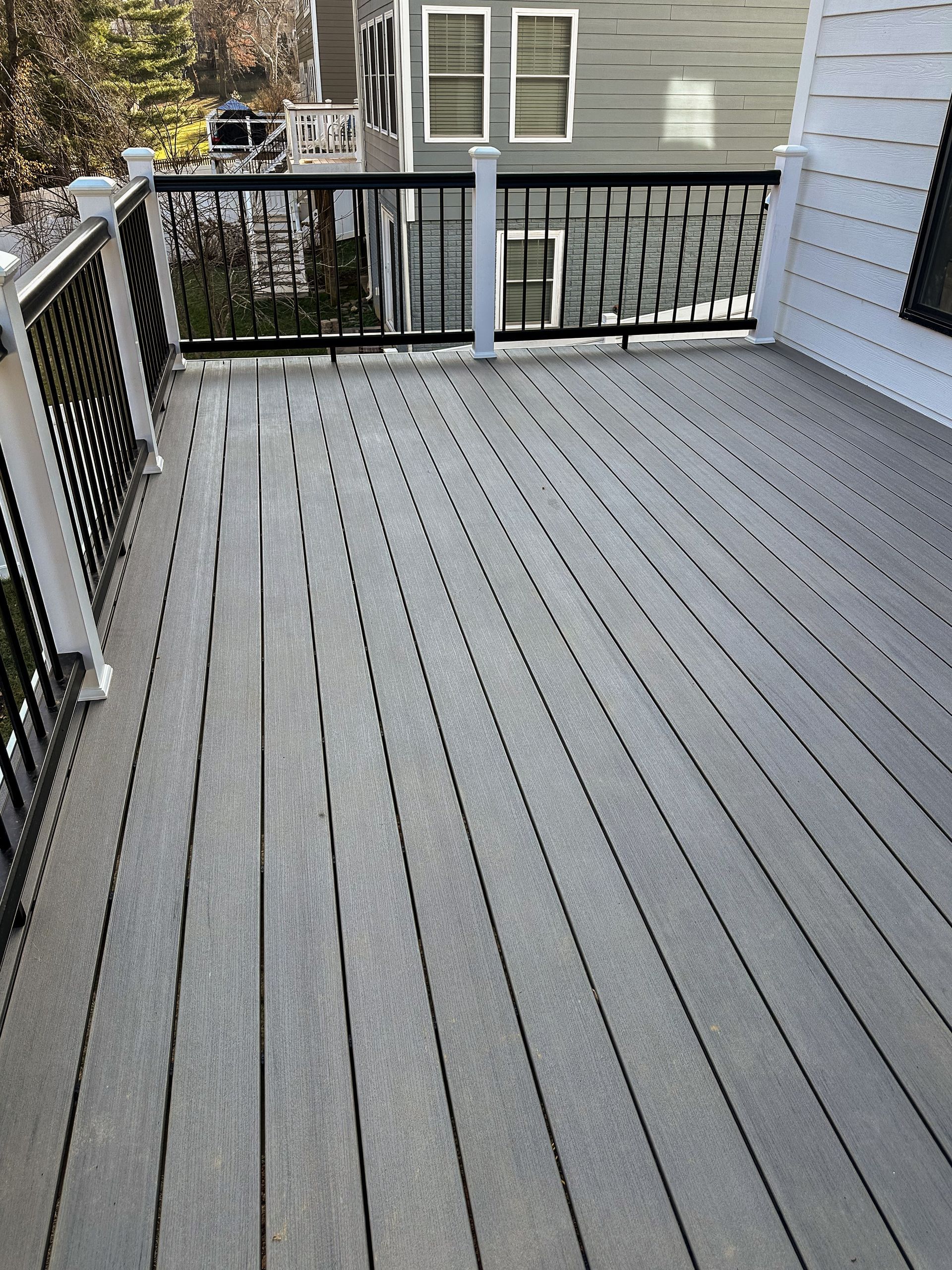 Gray composite deck with black railing and white posts, attached to a gray house.