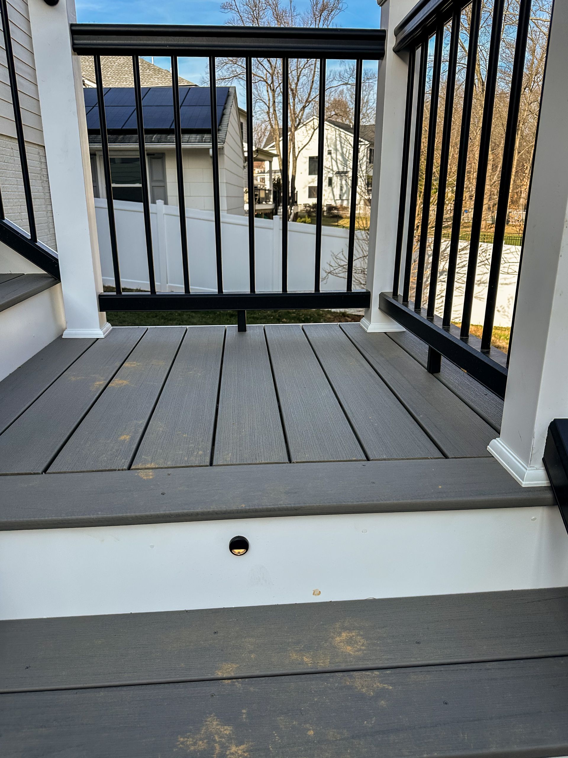 A gray composite deck with black railing and white supports.