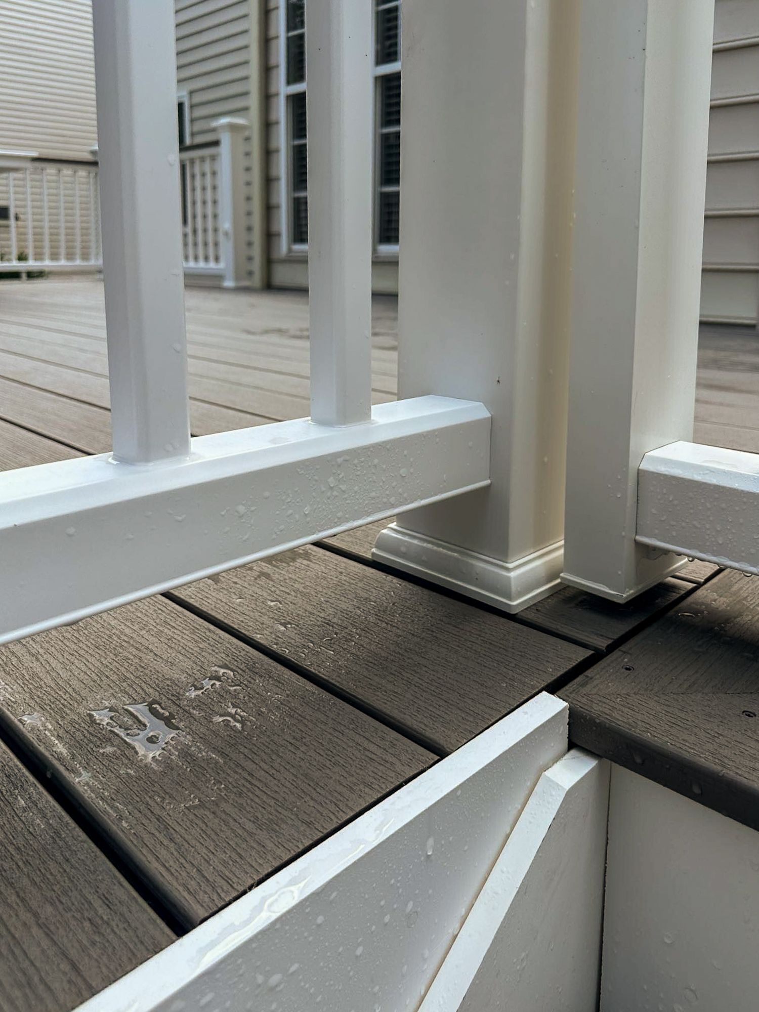 White deck railing and post on composite deck with brown boards.