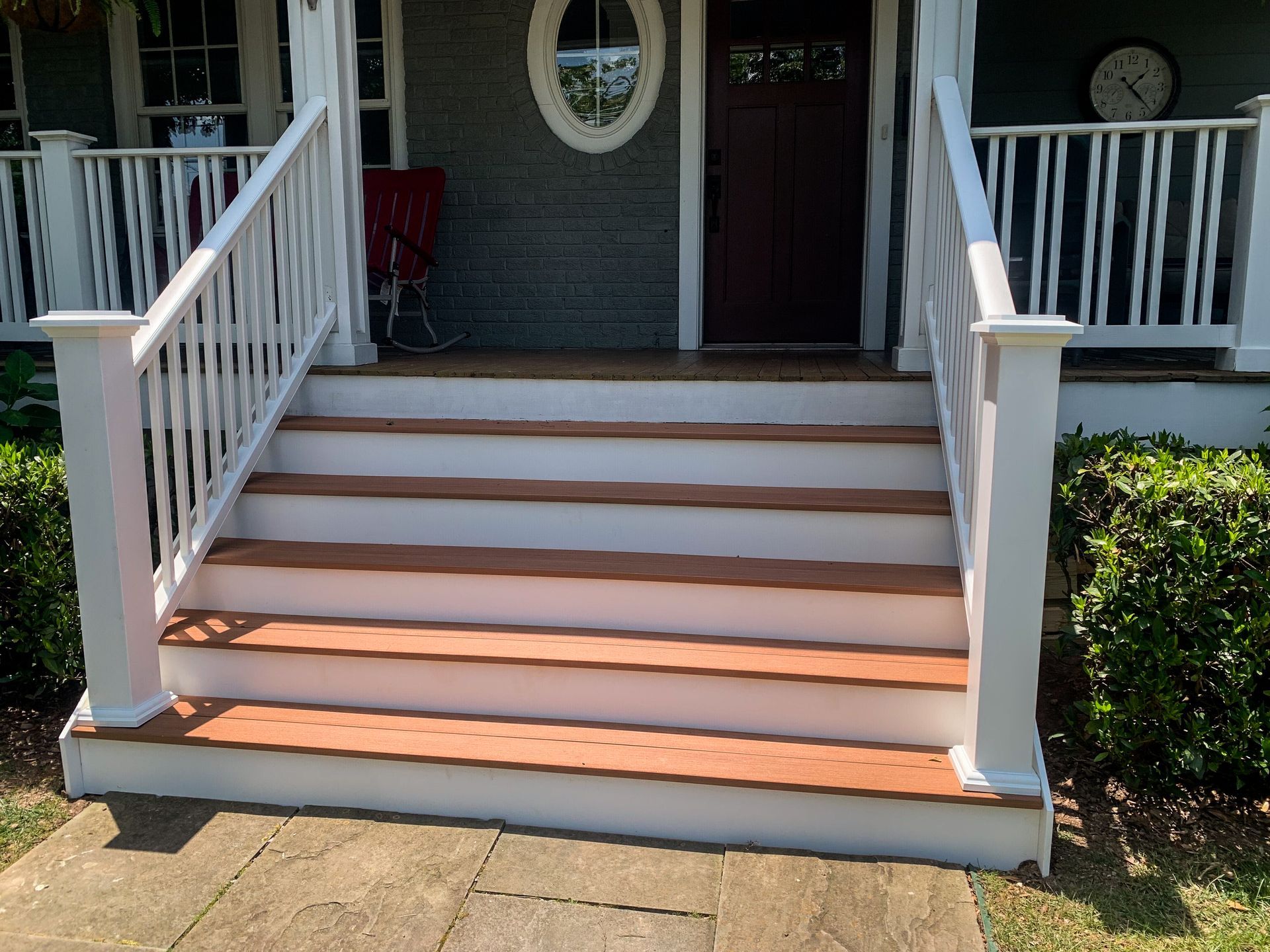 White-railed front porch stairs leading to a brown door. Brown steps with white risers.