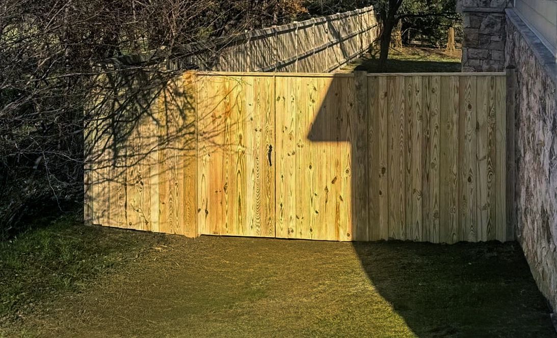 Wooden fence gate in a backyard. Sunlight and shadows on the gate and grass.