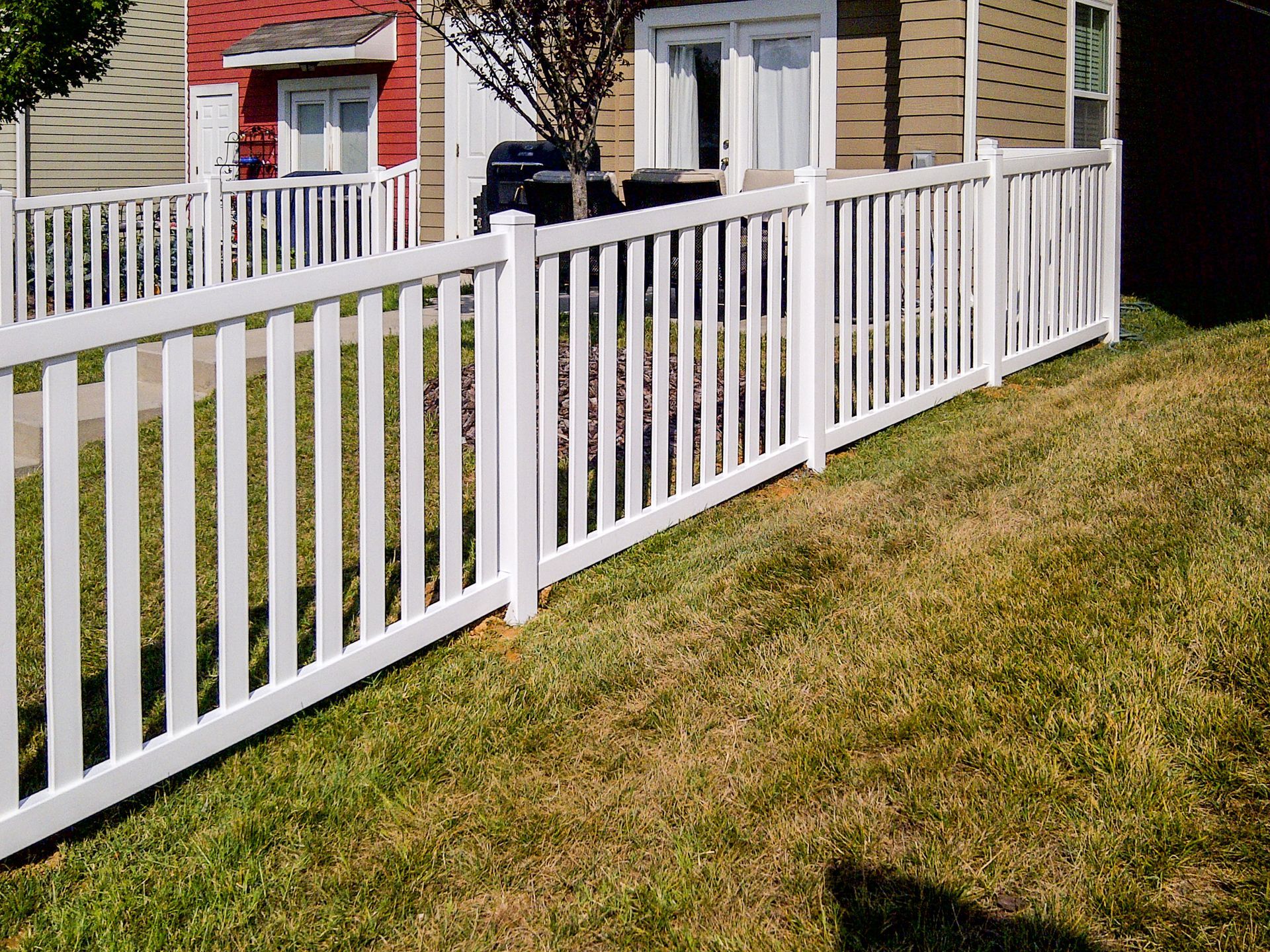 White picket fence in front of a building with grass.