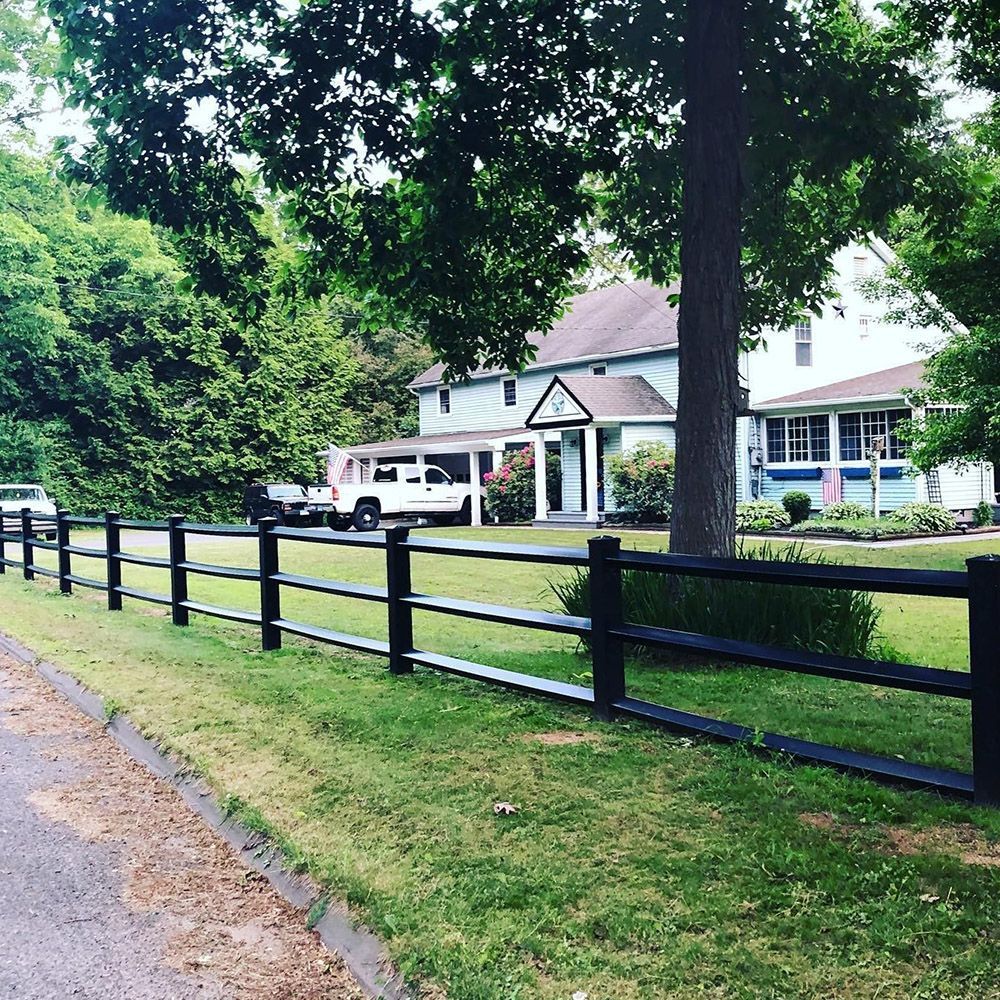 Black fence in front of green lawn and blue house with white trim.