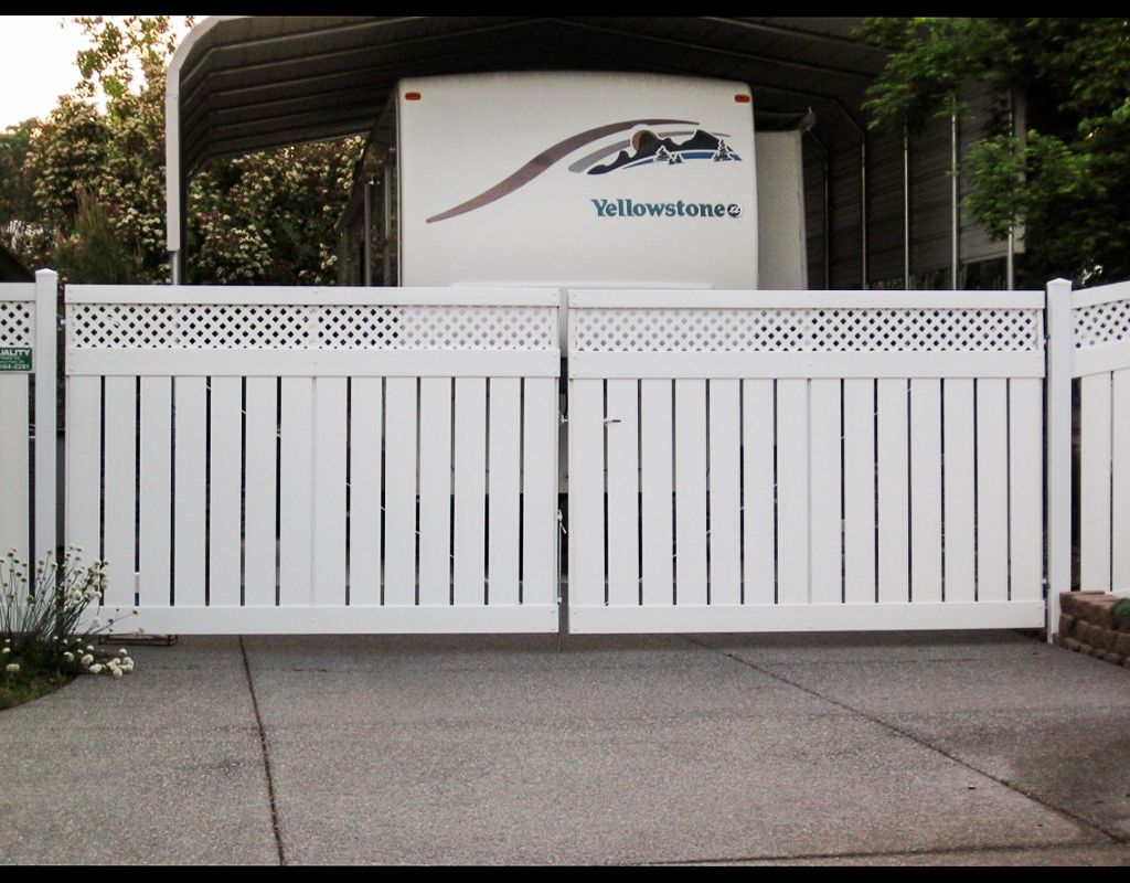 White double gate, open on a driveway. RV parked behind the gate.