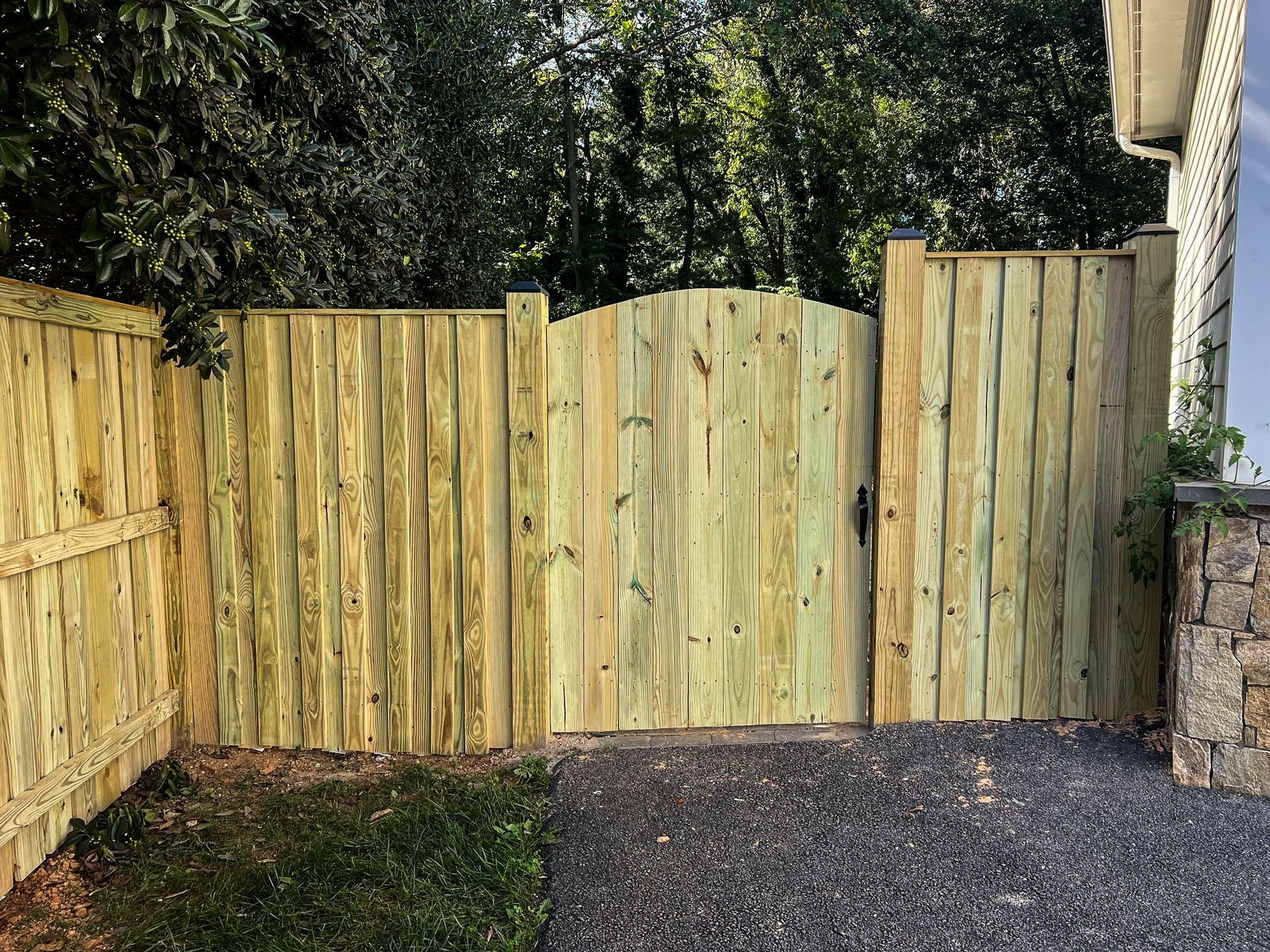 Wooden fence with a gate, green grass and gravel.