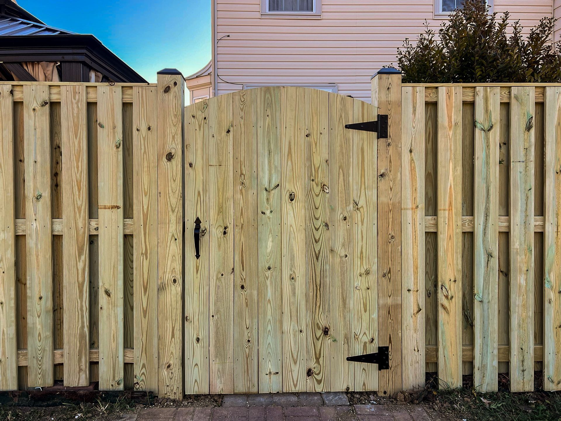 Wooden fence with gate, arched top, black hardware.