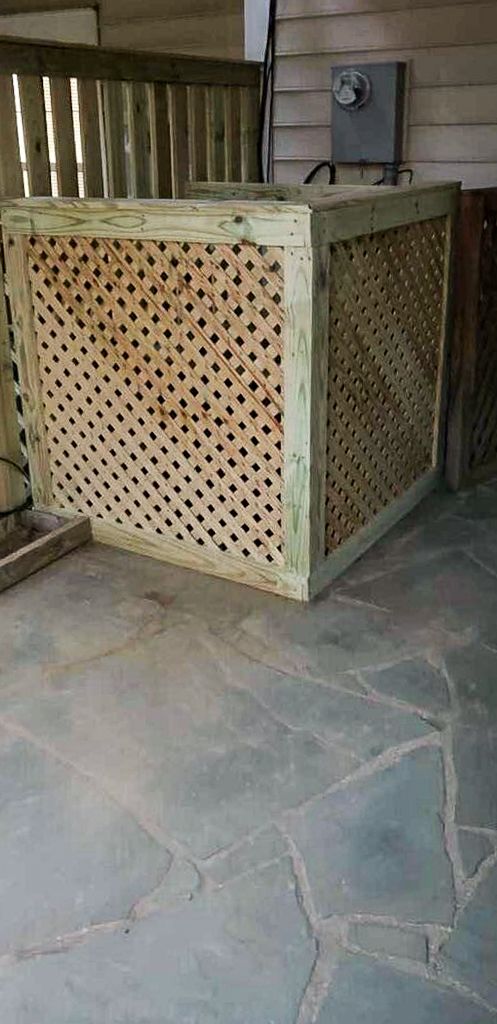 Wooden lattice box covering an electrical box on a stone patio.