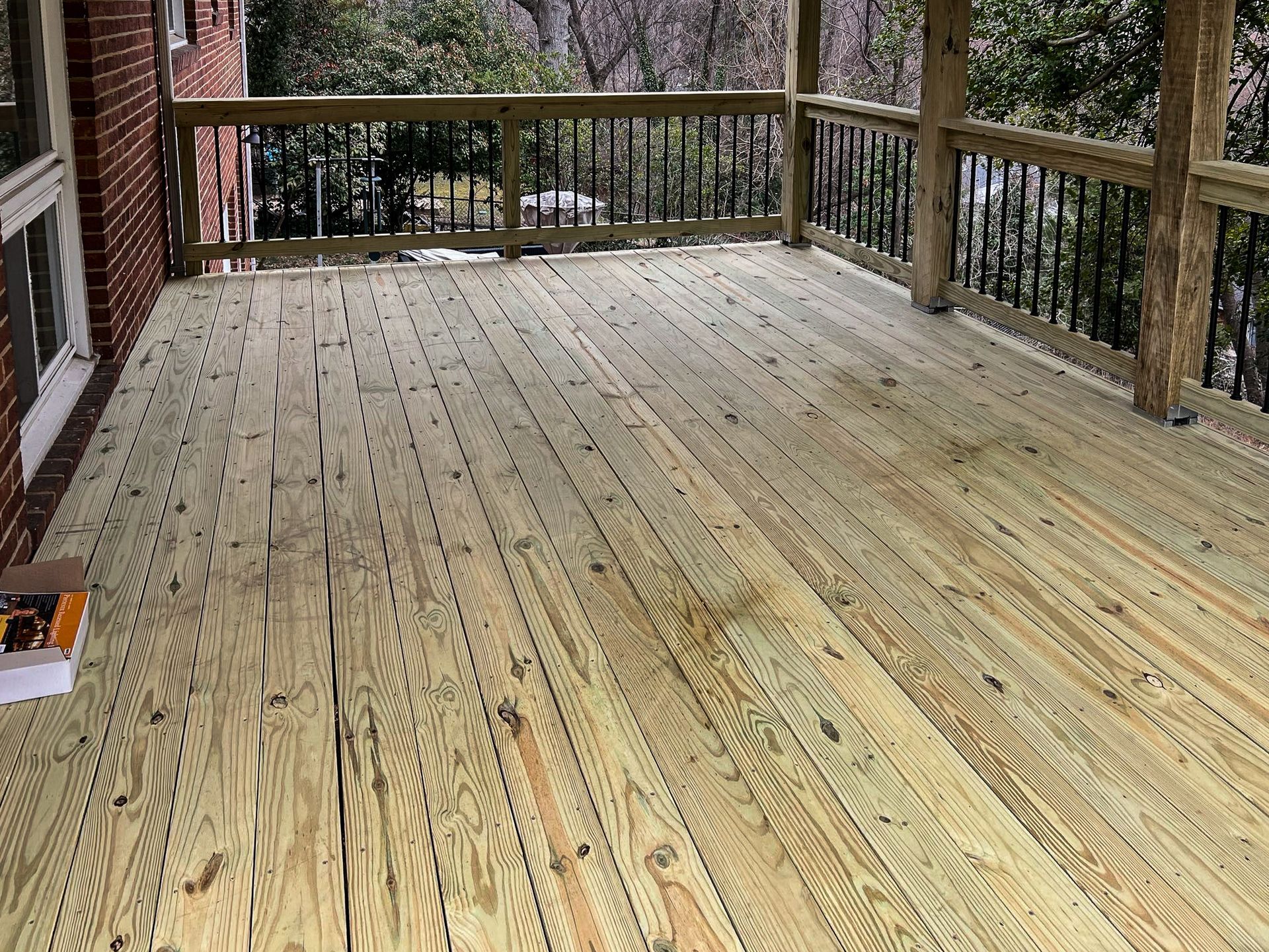Wooden deck with railings, attached to a brick house.