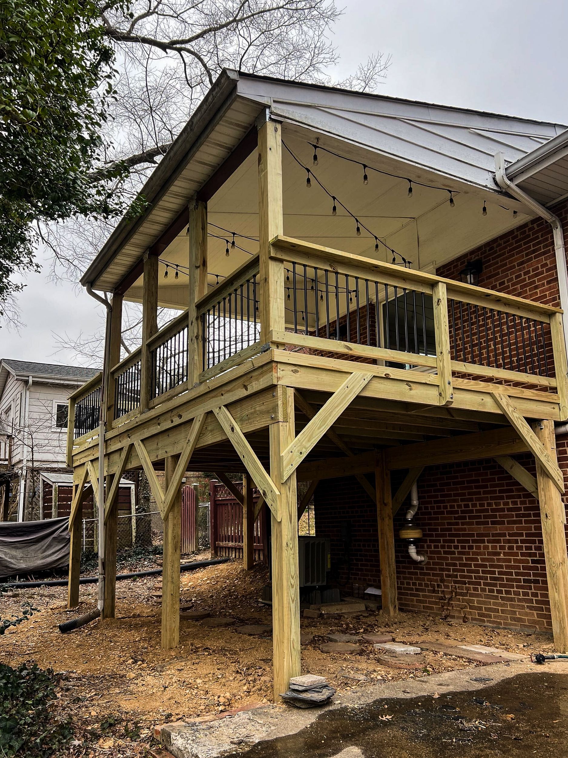 Wooden elevated deck attached to a brick house, under an overcast sky.