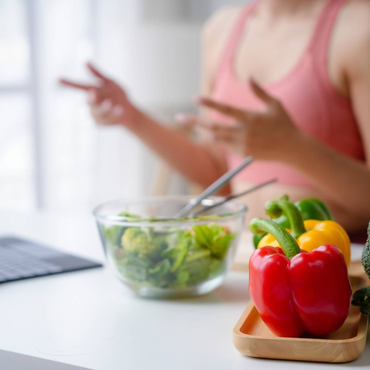 Woman gestures while discussing healthy food, including peppers and salad.
