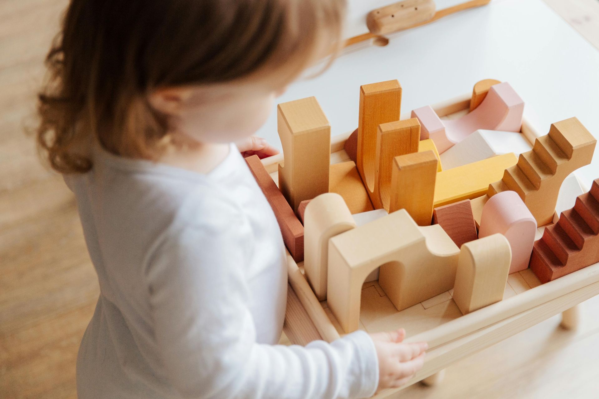 Child playing with wooden building blocks on a small table.