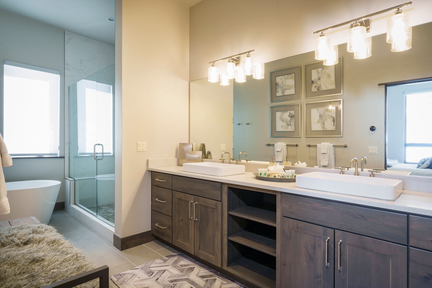Modern bathroom with double vanity, large mirror, and glass-enclosed shower. Neutral color palette with wood cabinets.