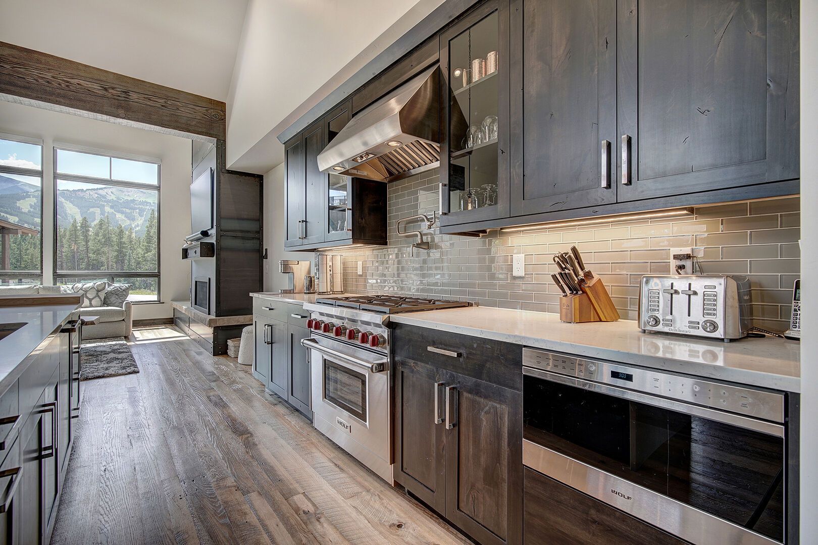 Modern kitchen with gray cabinets, stainless steel appliances, and a tiled backsplash.