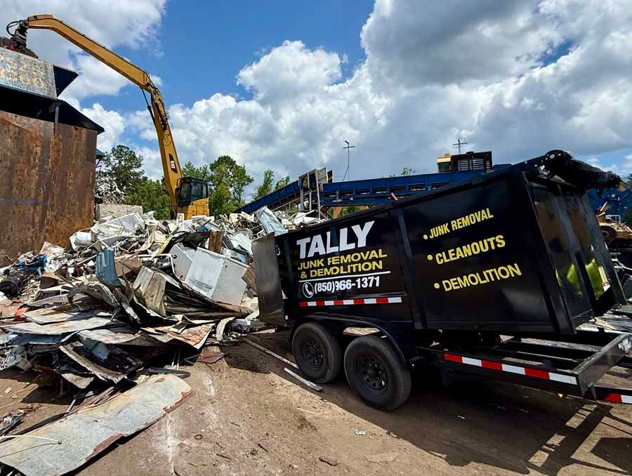 Excavator and dump trailer hauling construction debris at a demolition site under a cloudy sky