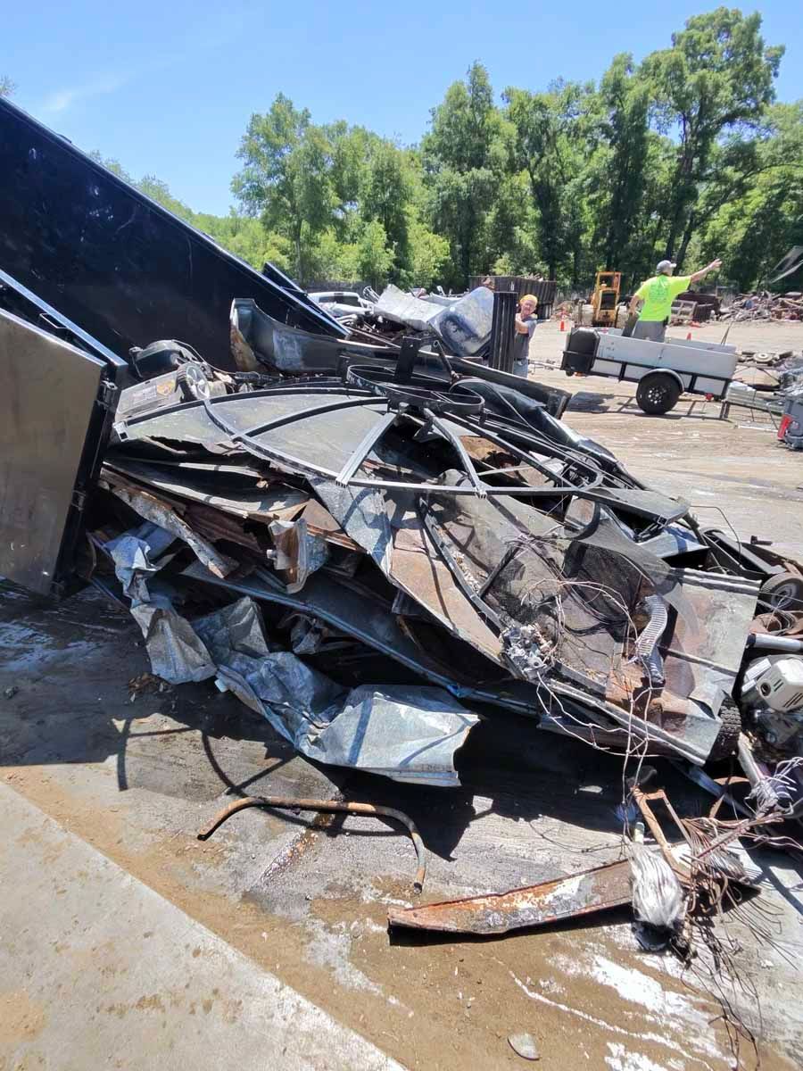 Burned-out car wreck with twisted metal on a roadside under bright daylight