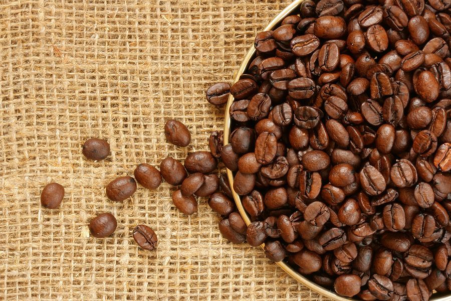 A bowl of coffee beans on a burlap cloth