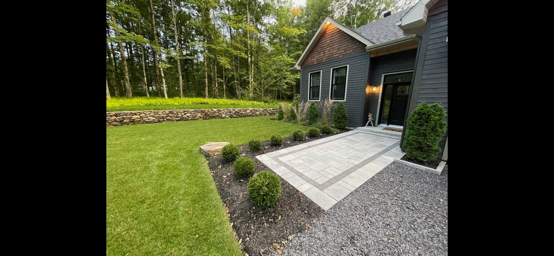 Une maison en brique avec une allée en gravier et un patio devant.