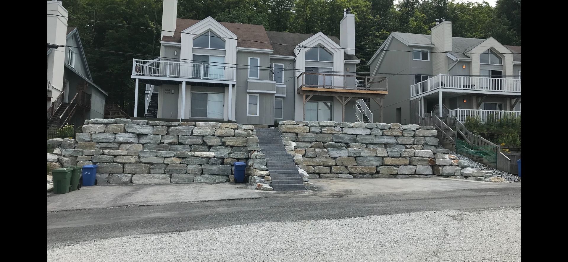 Une grande maison avec un grand mur de pierre devant elle.