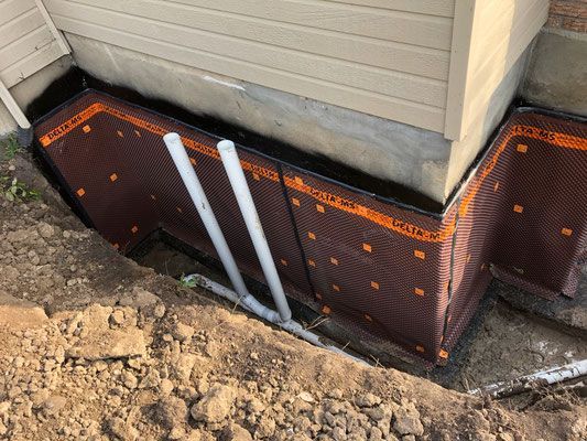 Un système de drainage est en cours d'installation sur le côté d'une maison.