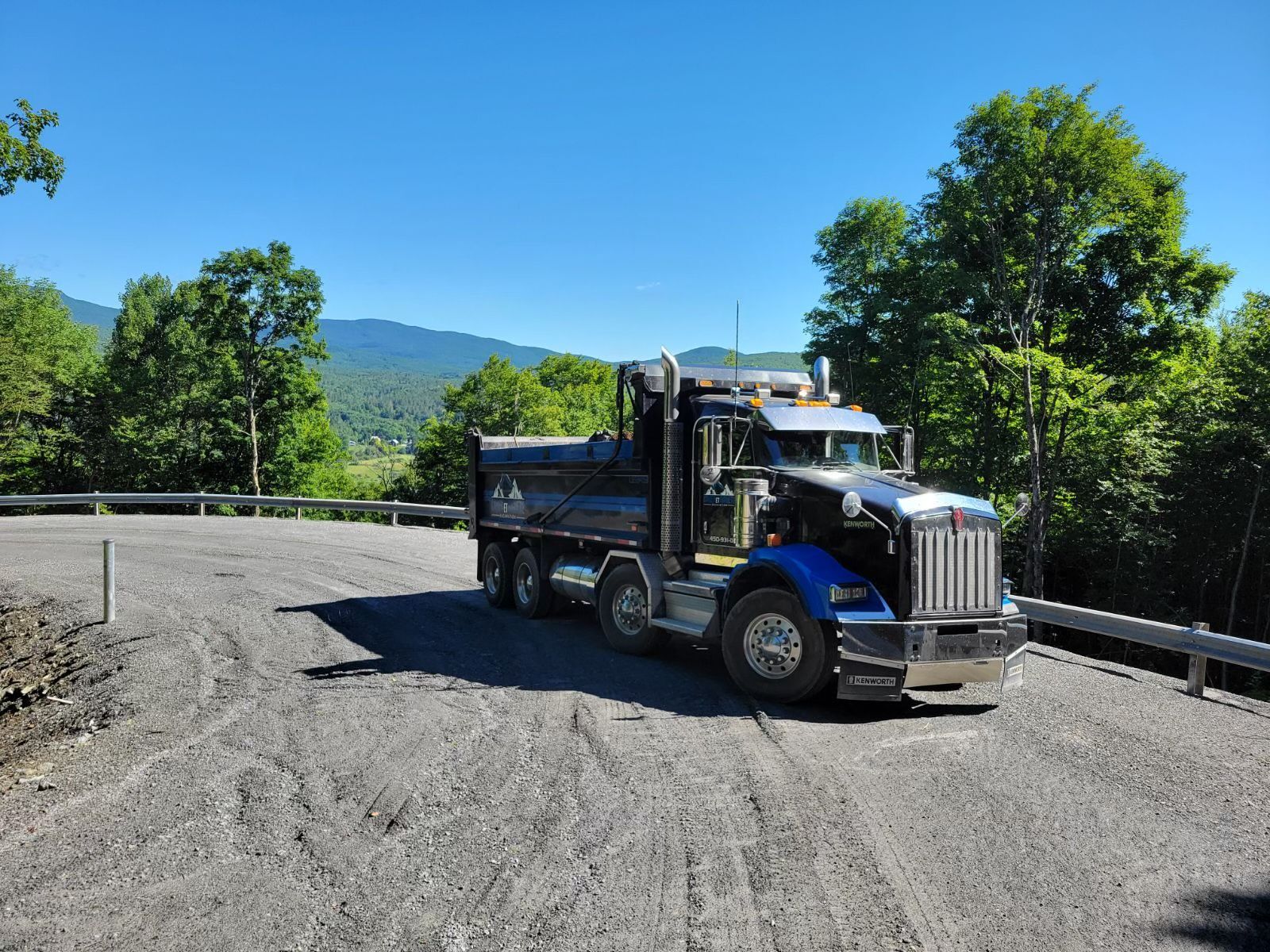 Un camion-benne bleu est garé sur le bord d'un chemin de terre.
