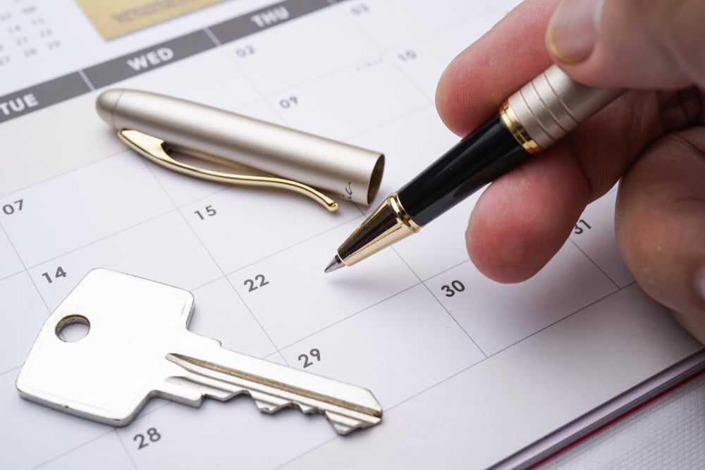 A Person Is Holding a Pen Over a Calendar Next to A Key — As Is Where Is in Auckland, NZ