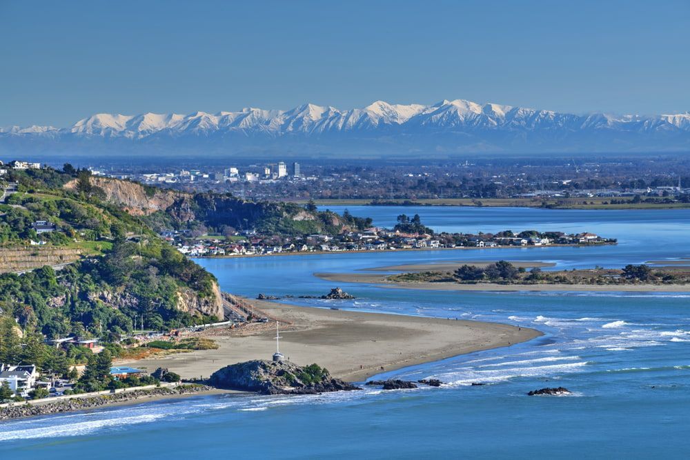 Sumner Bay In The Foreground Looking West Towards Redcliffs Bay And Christchurch City With The Southern Alps Framed Above In Early August — As Is Where Is in Christchurch, NZ