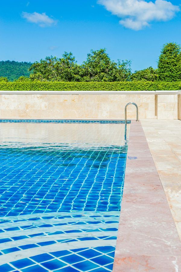 A swimming pool with blue tiles and a ladder in the water.