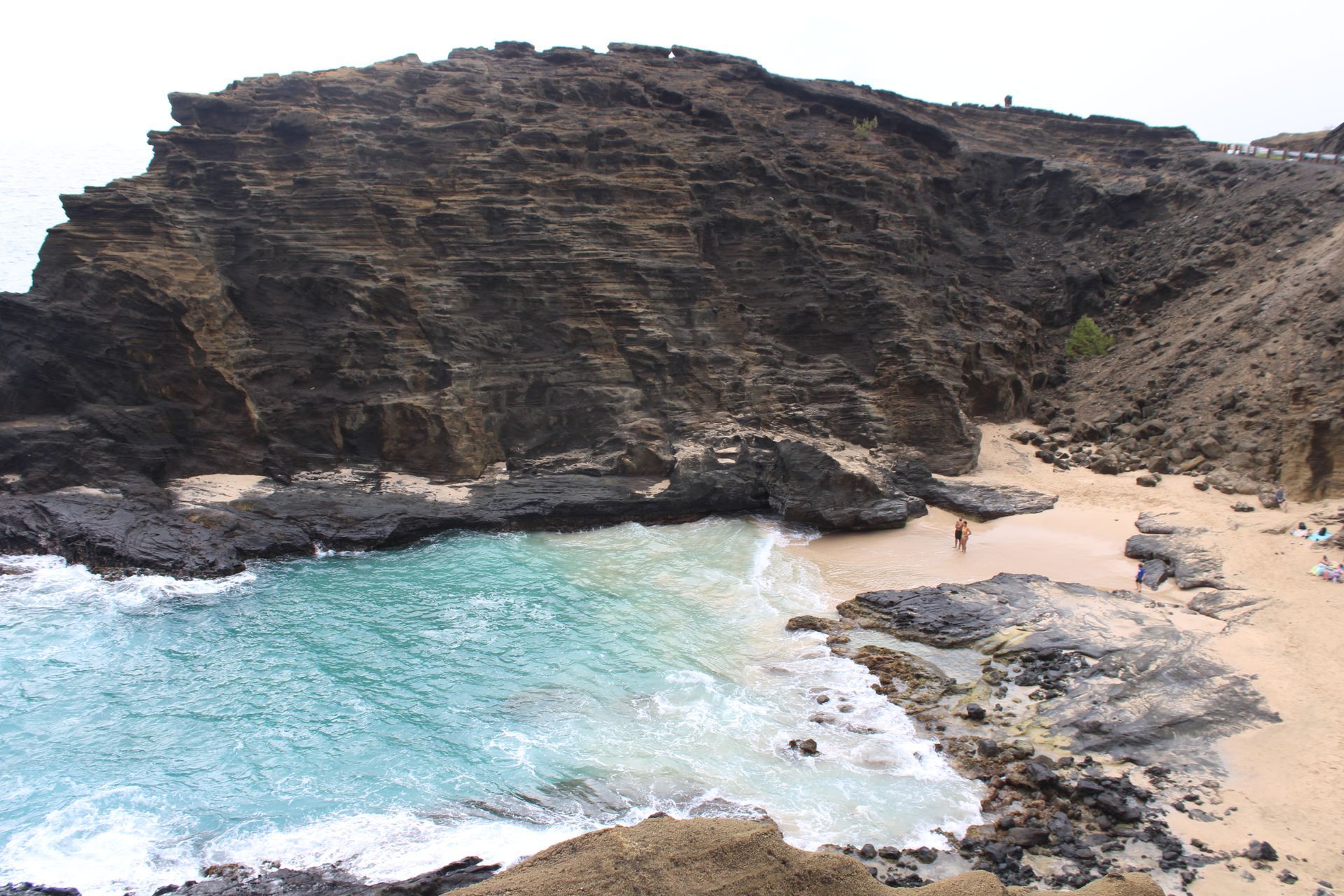 A beach with a large rocky cliff in the background