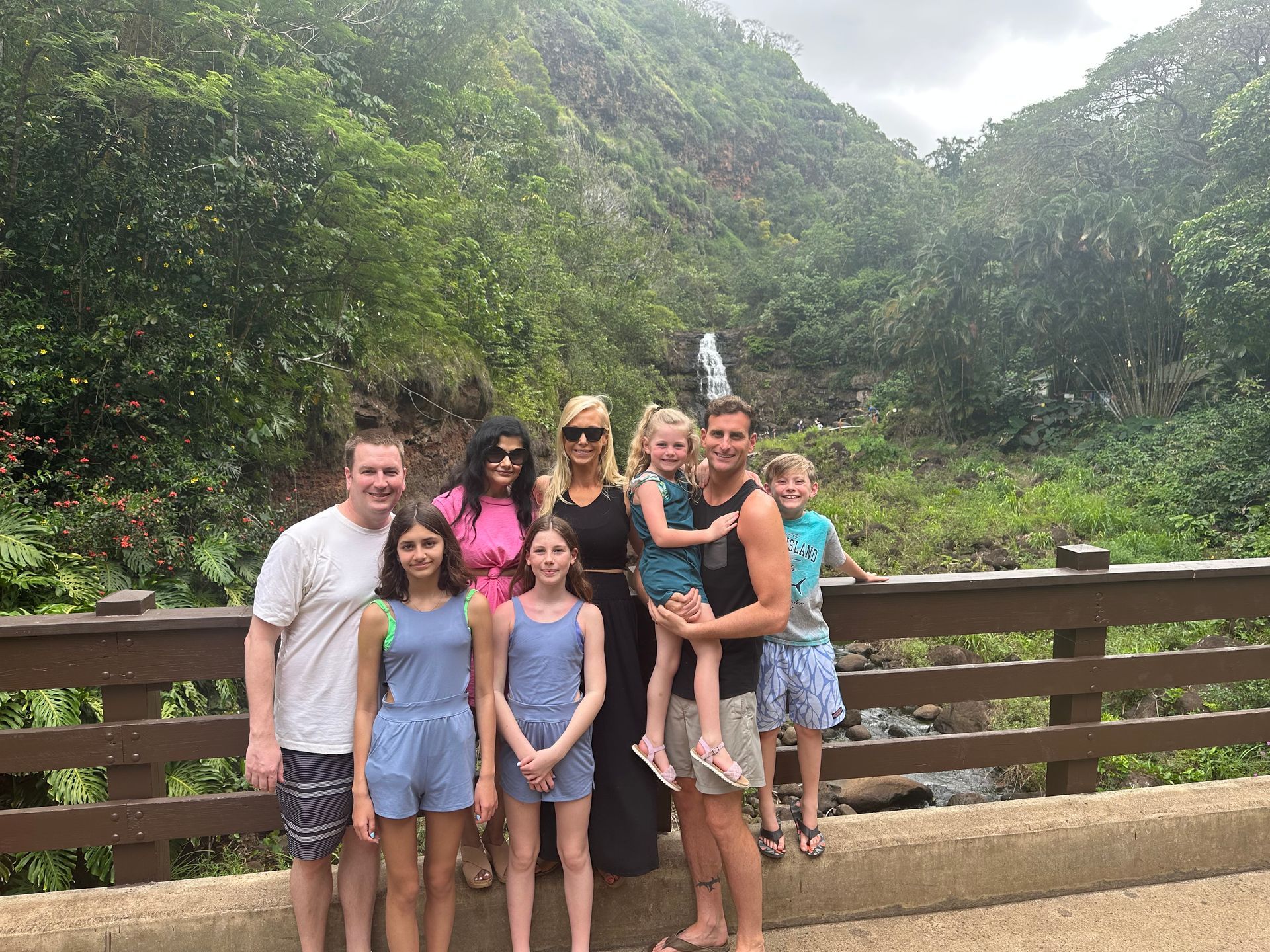 A family smiling and posing for a picture in front of a waterfall