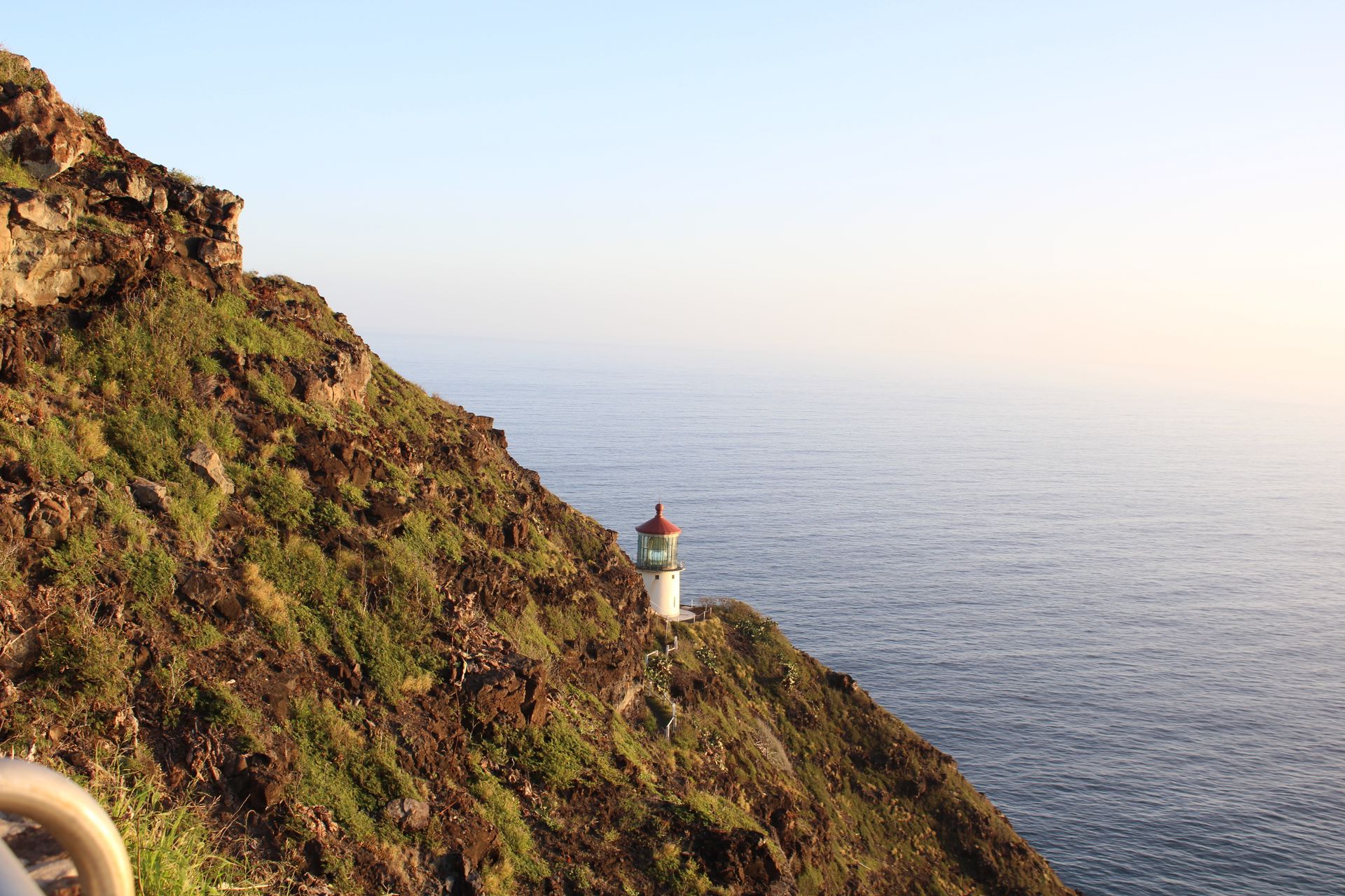 A lighthouse on a green, rocky cliff