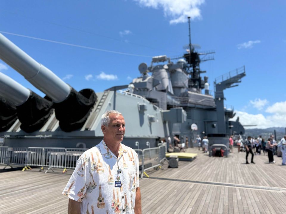 A man standing on a deck in front of a large ship