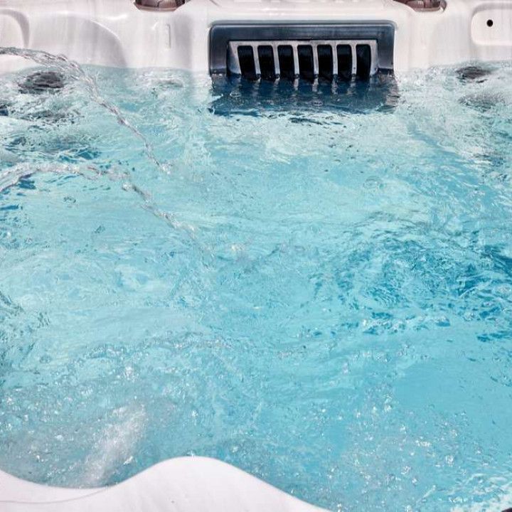 A hot tub filled with blue water and a drain