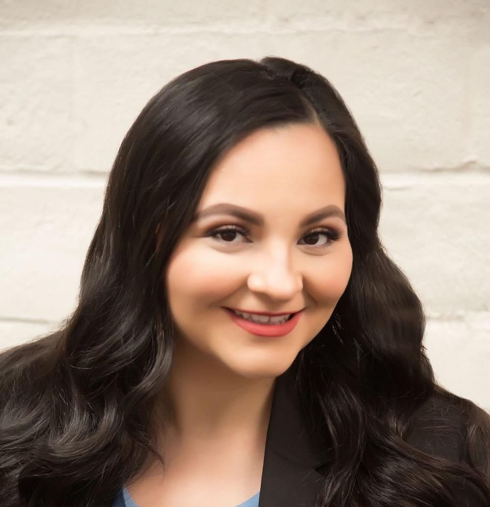 A woman with long dark hair is smiling for the camera