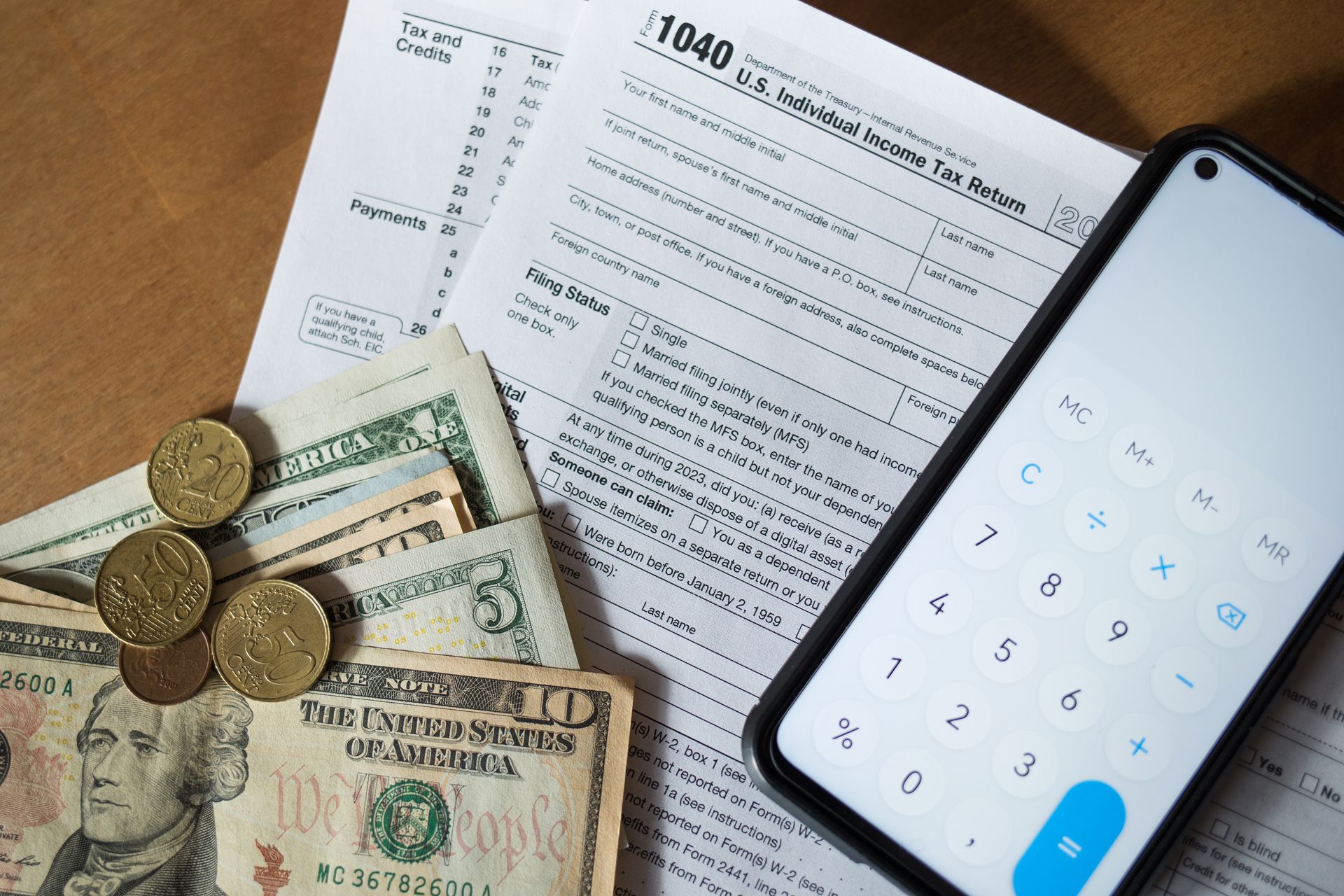 a cell phone sitting on top of a tax form next to money and coins .