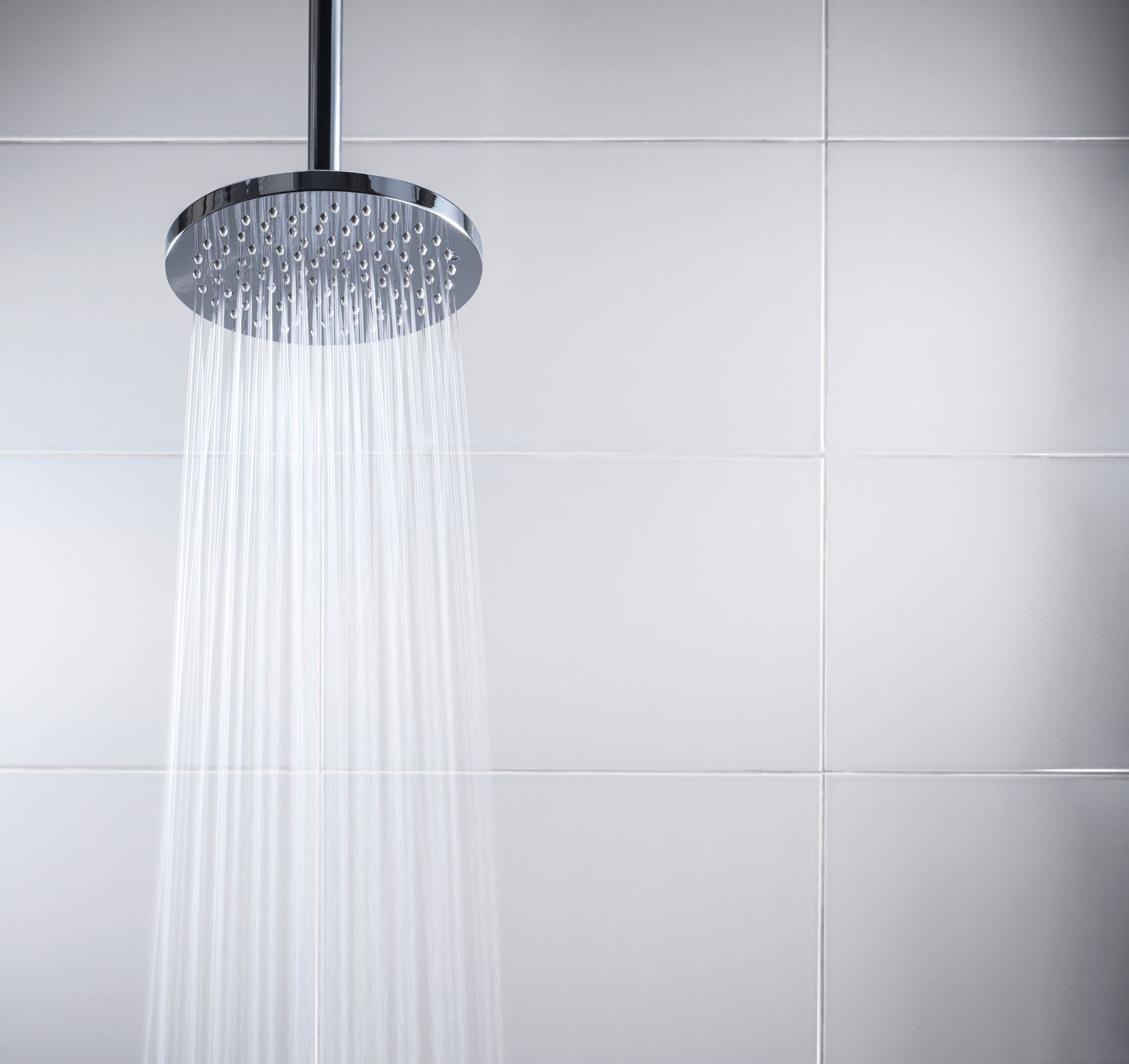 A shower head with water coming out of it in a bathroom.