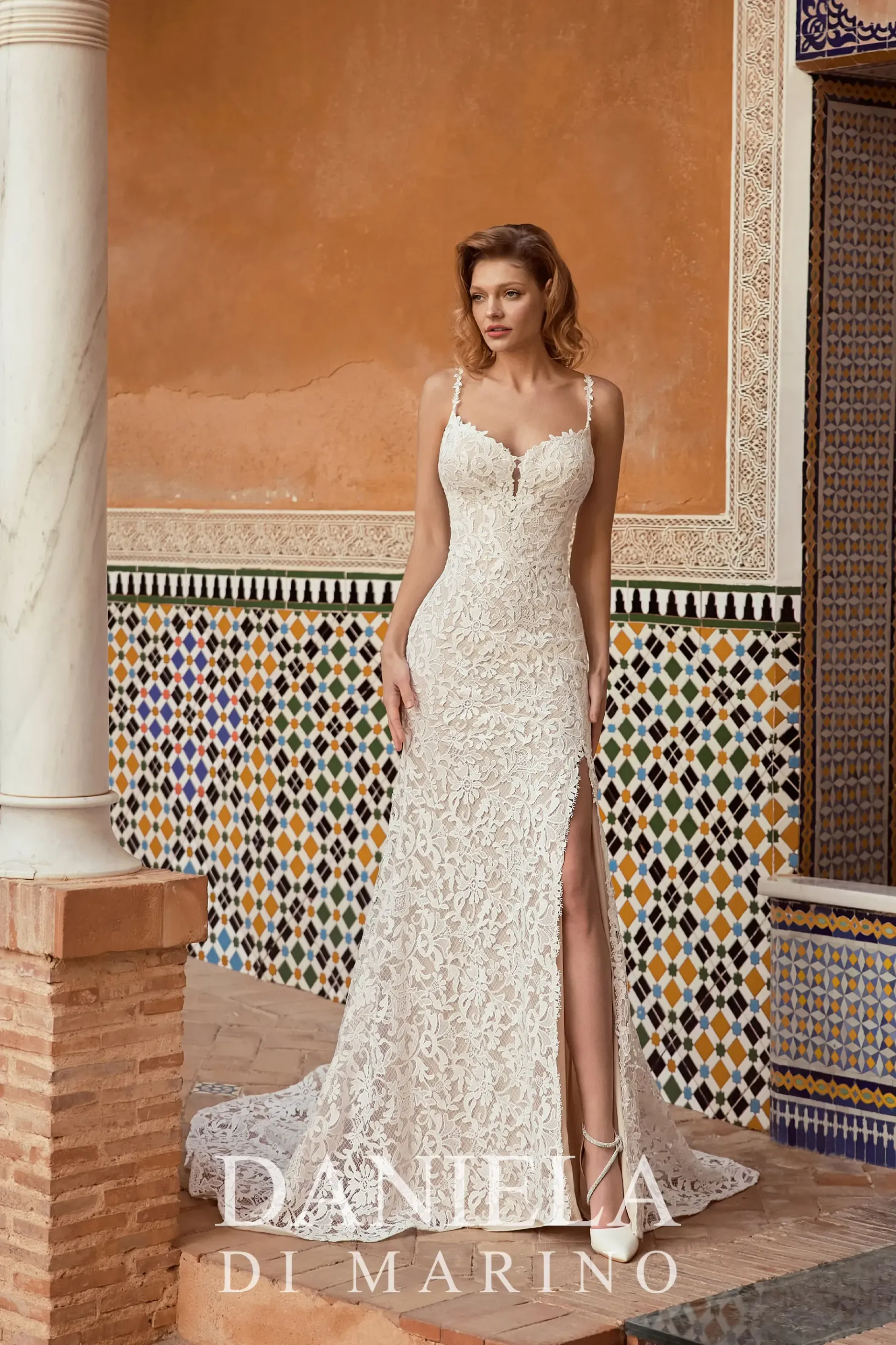 Bride in a white, beaded wedding dress with a plunging neckline, posing outdoors in a garden setting.