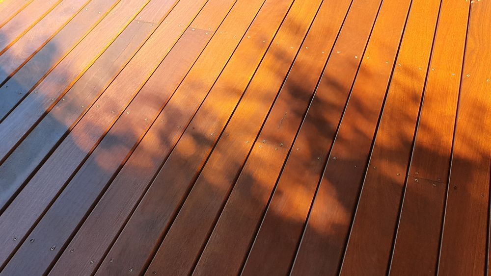 Wooden Deck Bathed in Golden Sunlight With Shadows of a Tree — Dachboe Your Handyman In Ayr, QLD