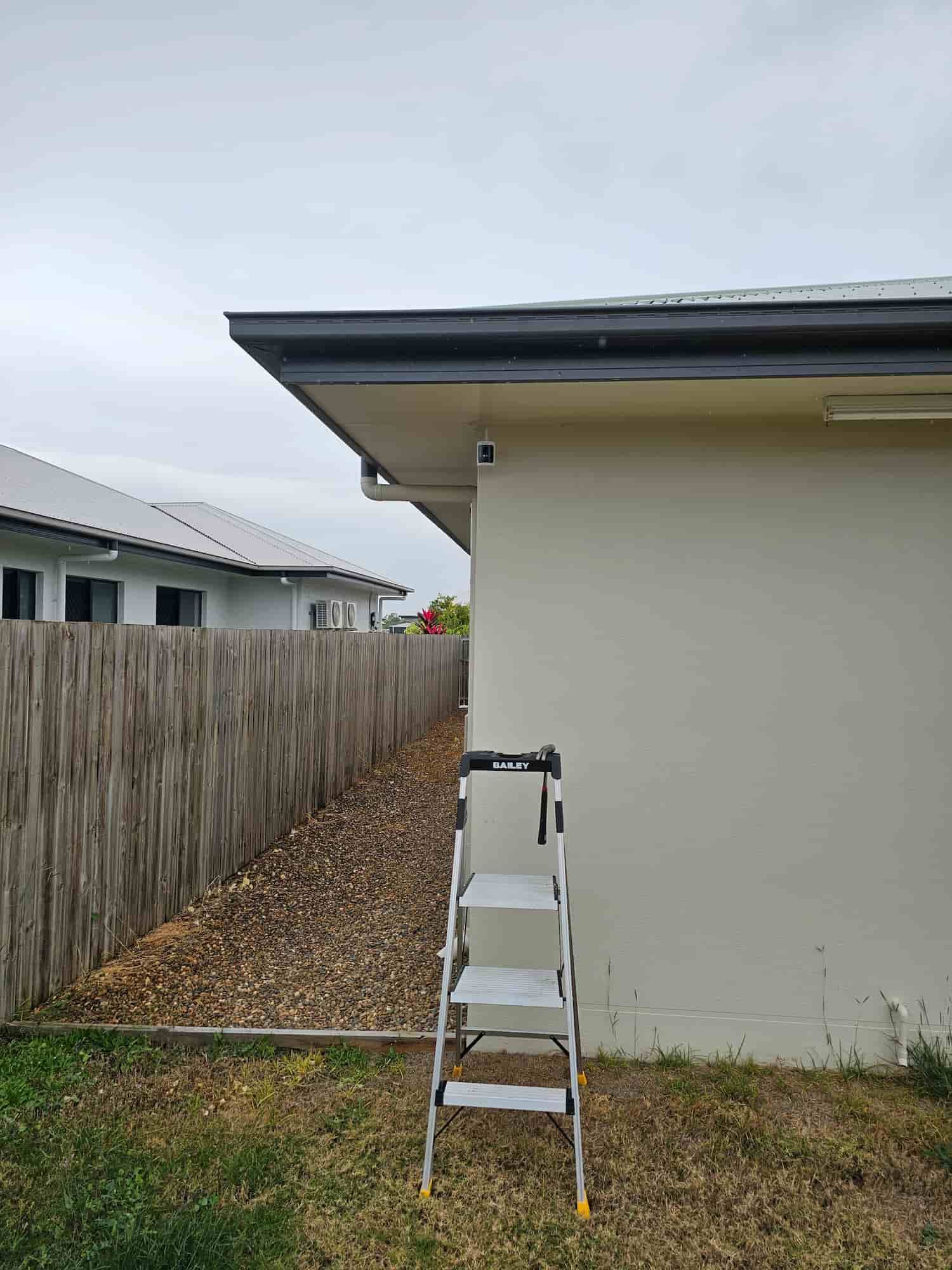 A Ladder Is Sitting On The Side Of A House Next To A Wooden Fence — Dachboe Your Handyman in Townsville, QLD