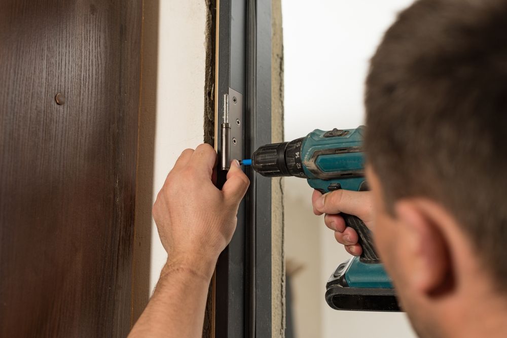 Man Using a Power Drill to Install a Hinge on a Door Frame — Dachboe Your Handyman In Ayr, QLD