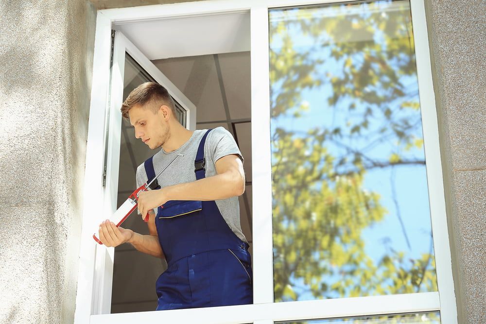 A Man Is Installing A Window On A Building — Dachboe Your Handyman in Ingham, QLD