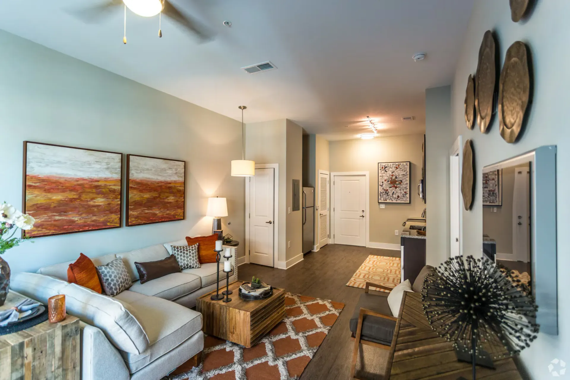 Open-concept living room in an apartment with a gray sectional, wooden coffee table, and wall art.