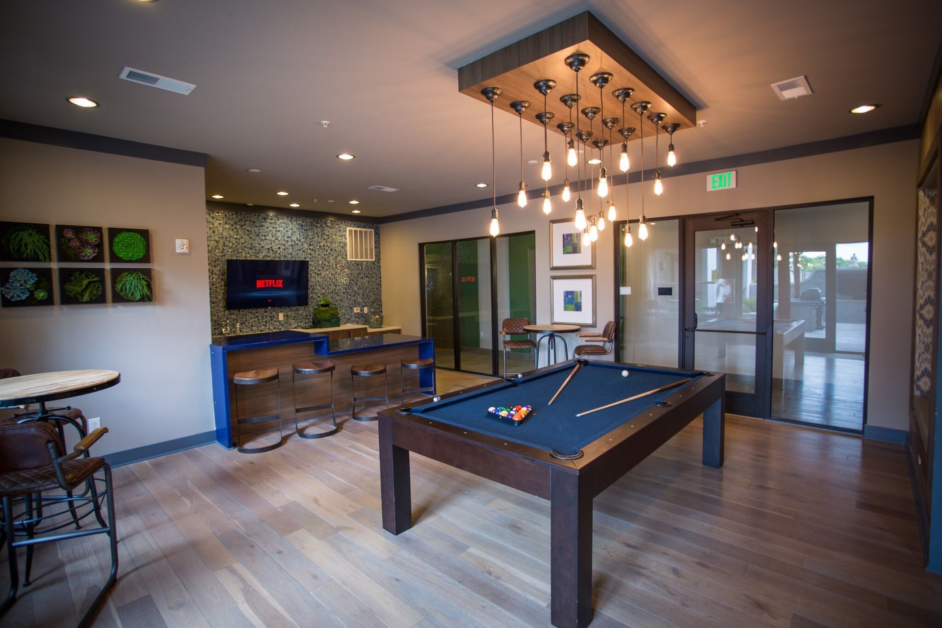 Indoor community recreation room with a pool table, bar area, and seating.