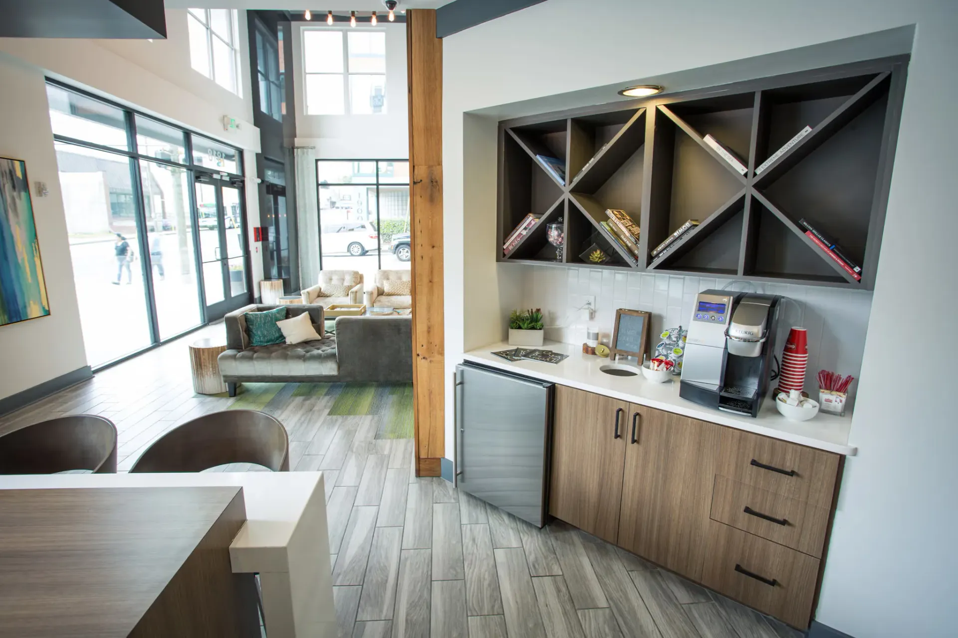 Lobby area of a modern apartment community with seating, coffee station, and storage cabinets.