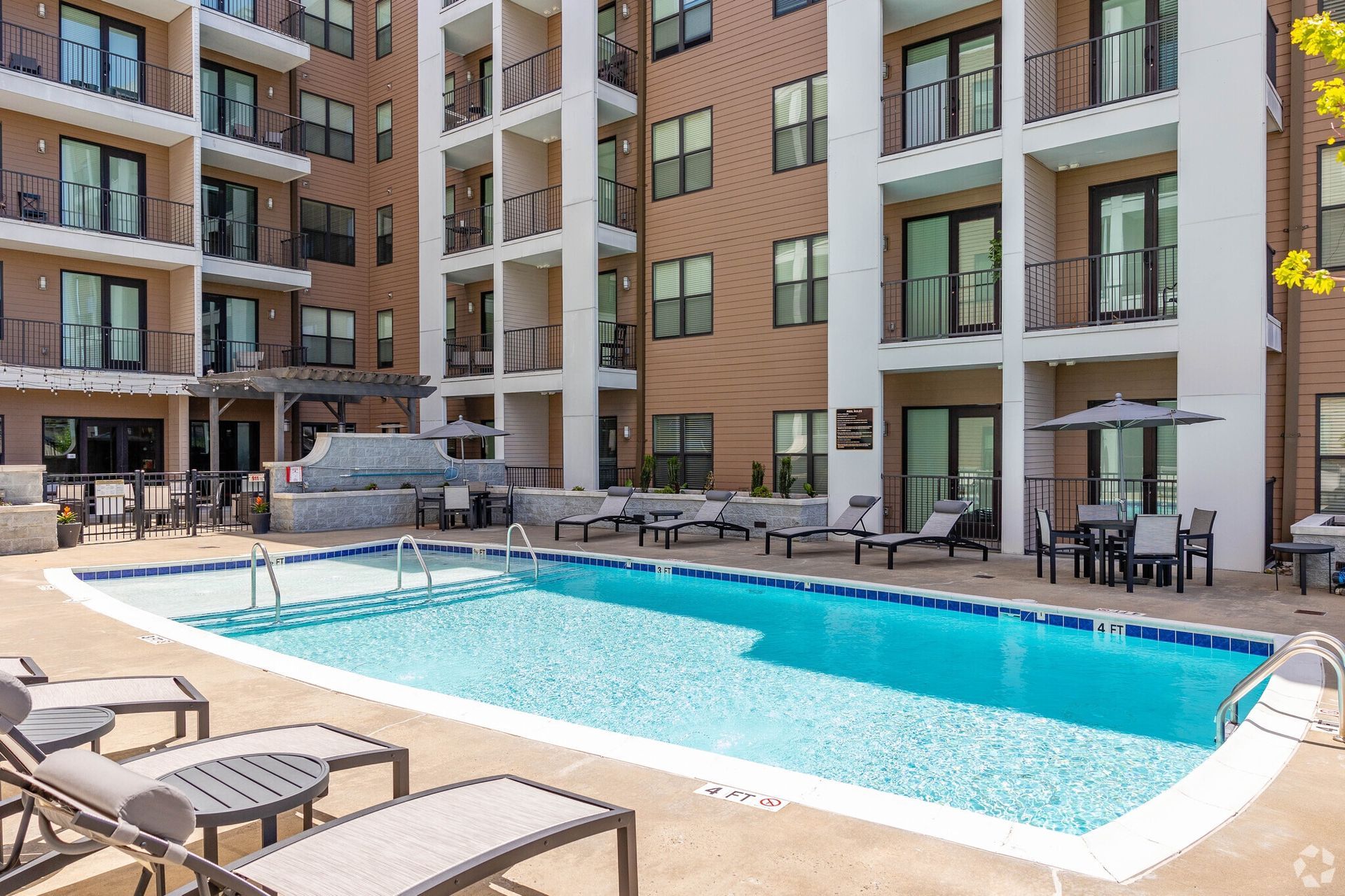 Outdoor pool area at an apartment complex with lounge chairs and seating.