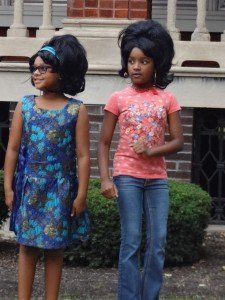 Two young girls standing next to each other in front of a brick building